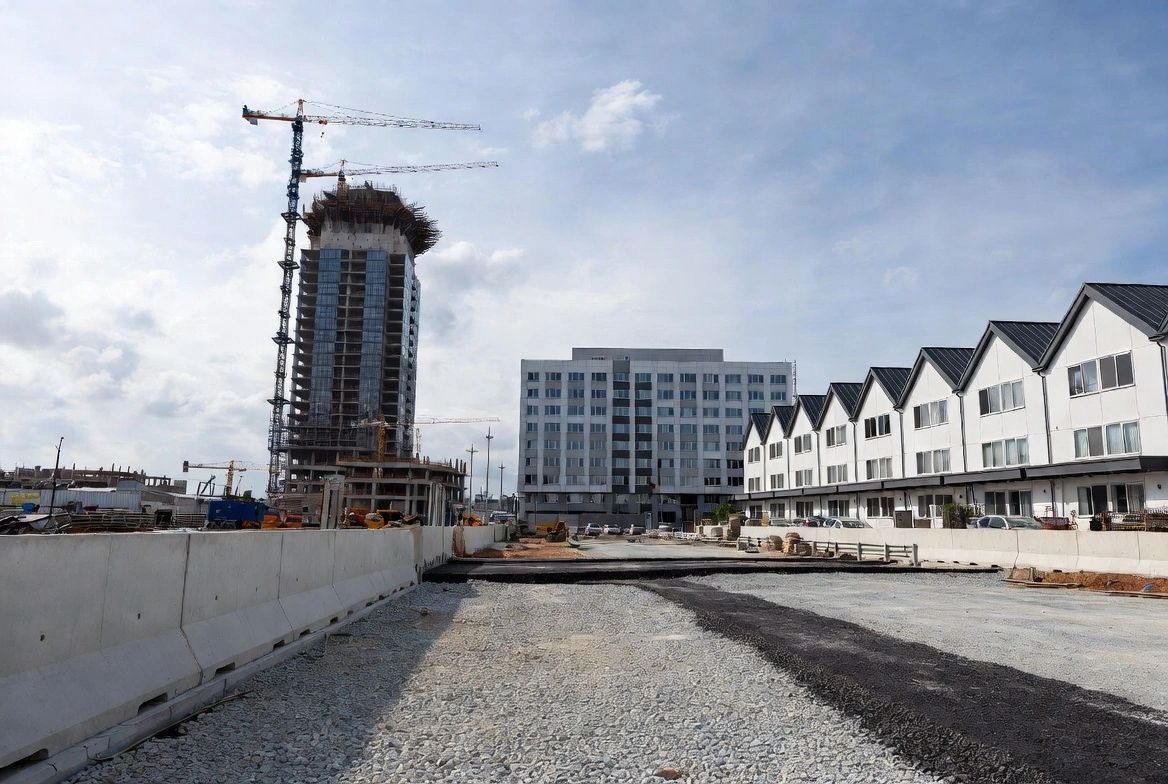 Wide view of a development with buildings, tower cranes and road works